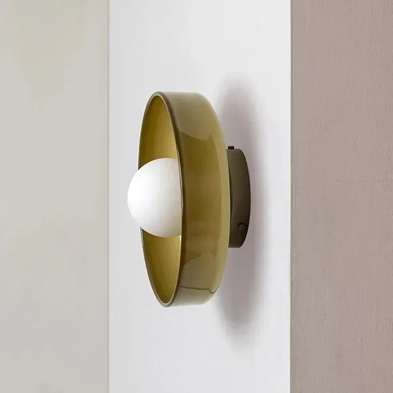 Væglampe i moderne design med olivengrøn skærm og hvid pære, monteret på hvid væg. Stilfuld belysning til hjemmet.
