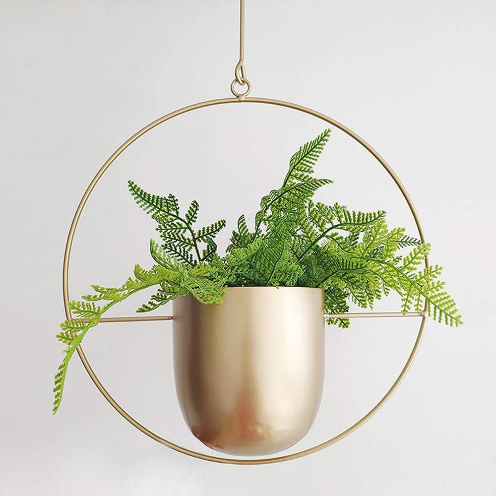 Hængende plante i gylden krukke med bregne, moderne indretning, minimalistisk design, indendørs planteophæng, stilfuld boligindretning.