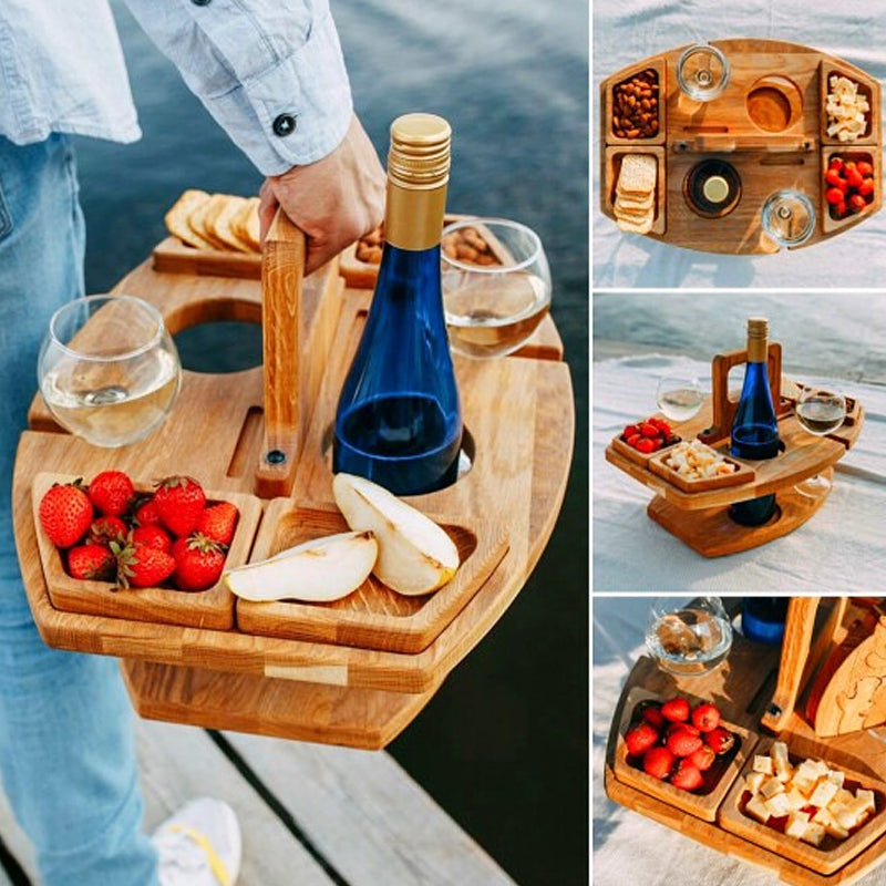 Bærbar picnicbakke i træ med vinflaske, glas, jordbær, pærer og snacks. Perfekt til udendørs hygge ved vandet. Ideel til sommerpicnic.