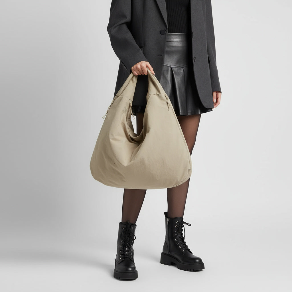 Kvinde i sort outfit med beige, stor skuldertaske, læder nederdel og snørestøvler. Mode, accessories, moderne stil, streetwear.