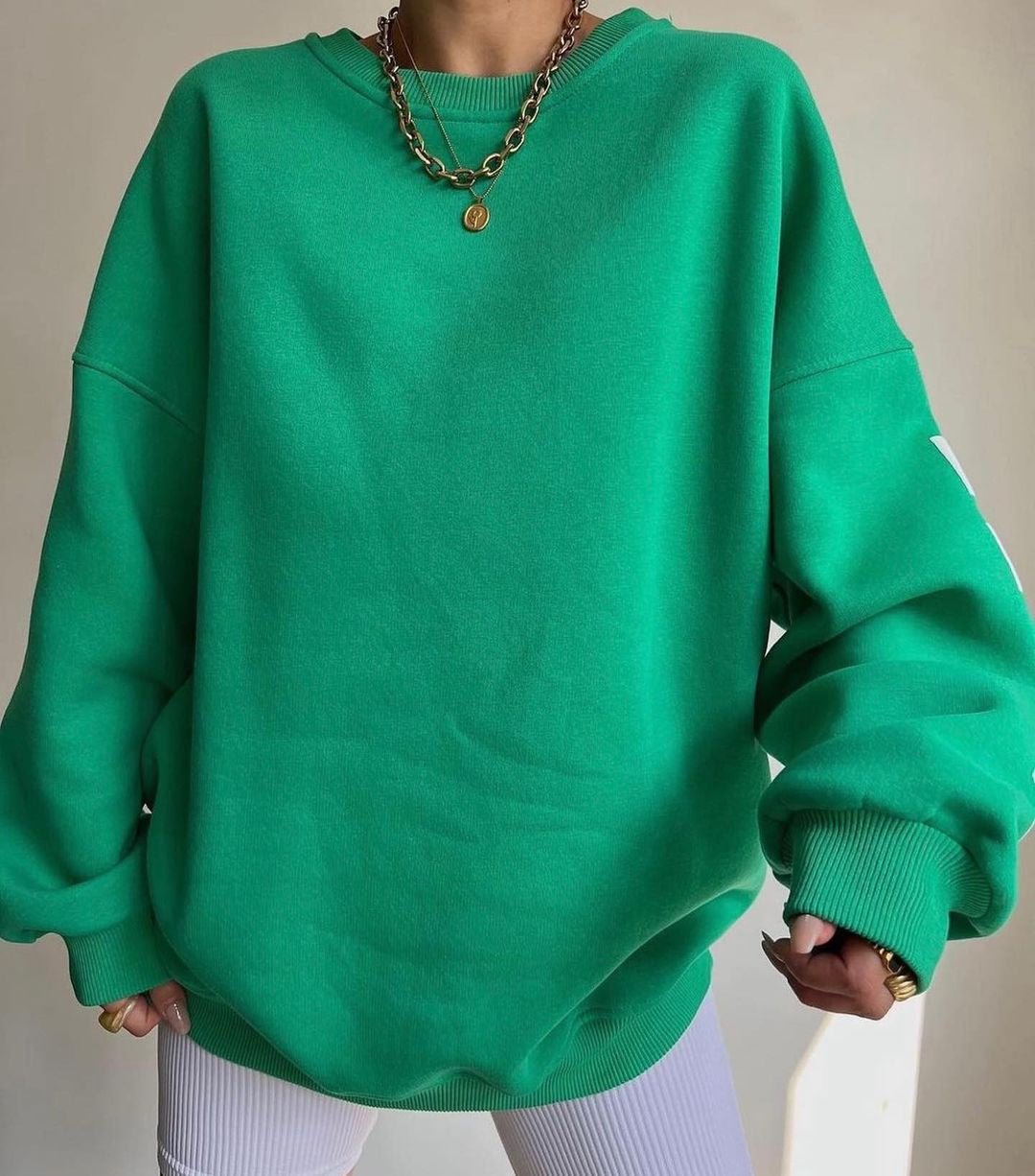 Grøn oversized sweatshirt, guldhalskæde, hvid baggrund, trendy mode, afslappet stil, komfortabelt tøj, moderne design, streetwear look.