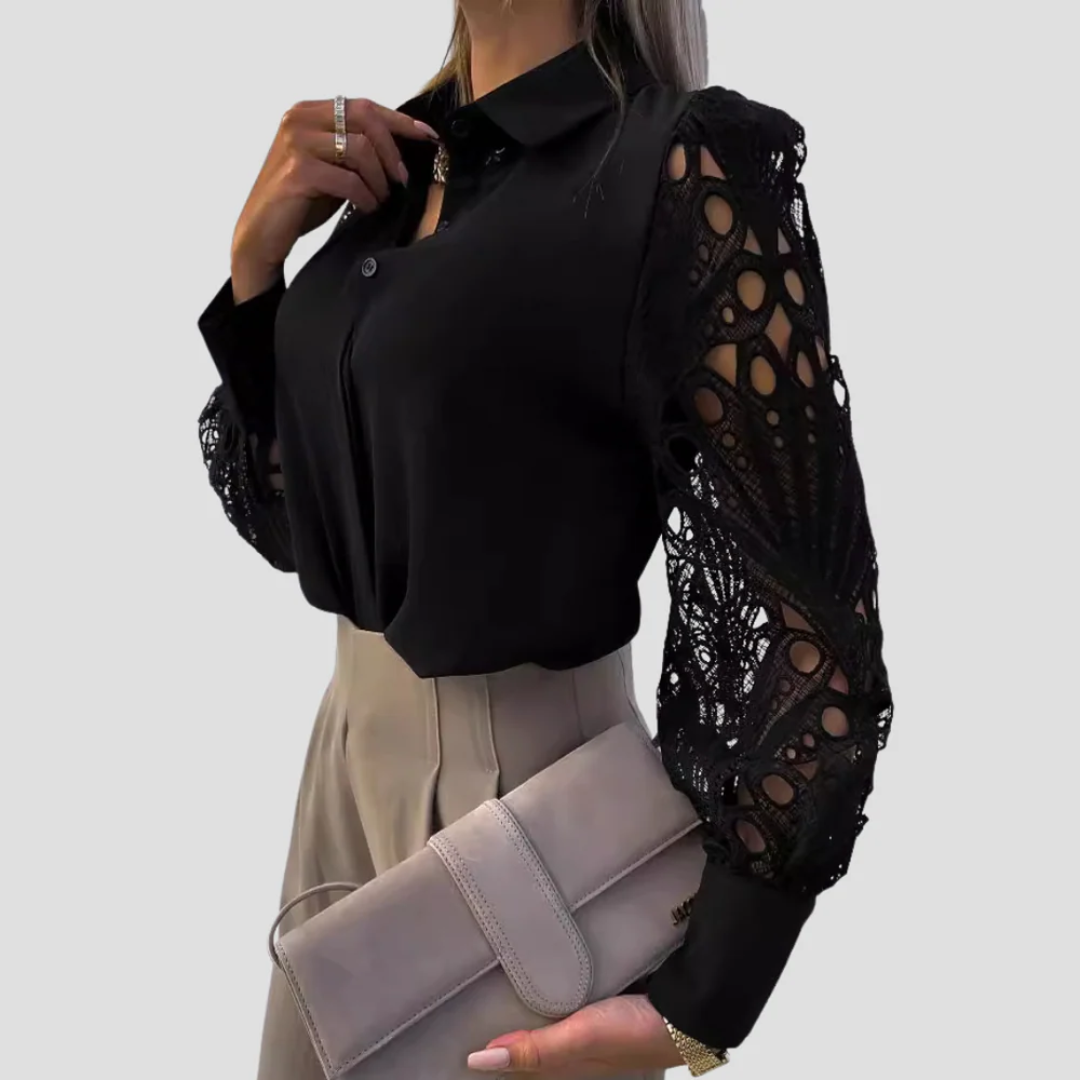 Kvinde iført sort bluse med blondeærmer, beige bukser og holder en grå clutch. Elegant mode, stilfuldt outfit, moderne kvindetøj.