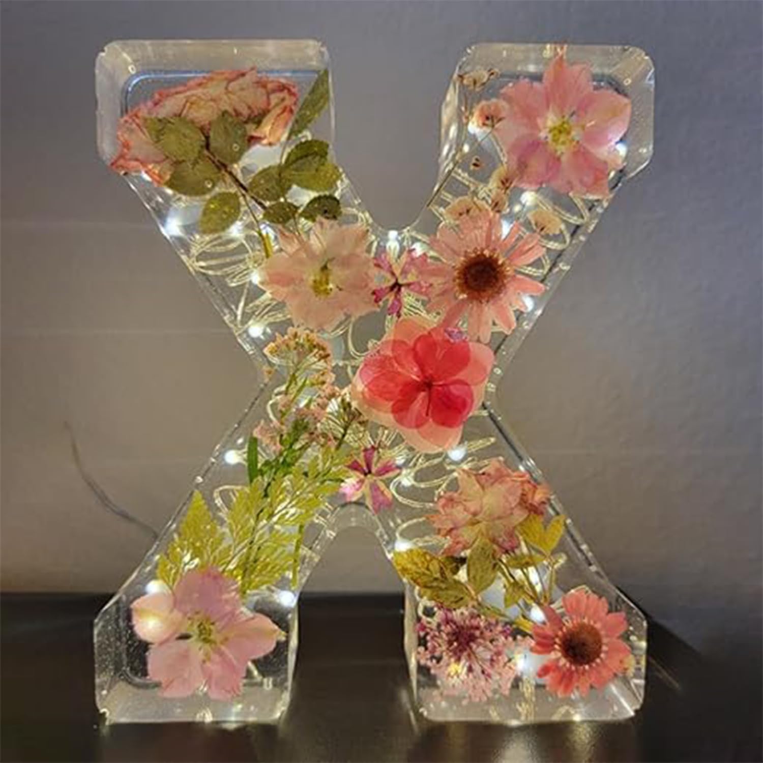 Dekorativt bogstav "X" med indlejrede tørrede blomster og LED-lys, perfekt til boligindretning. Unik gaveidé, der kombinerer natur og lysdesign.