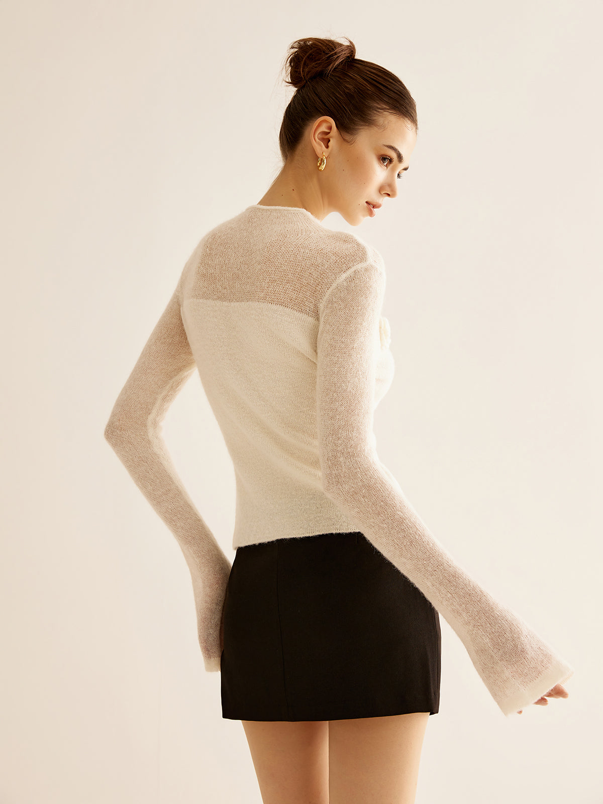 Kvinde iført hvid, langærmet trøje og sort nederdel. Elegant mode, minimalistisk stil, moderne kvindetøj, trendy outfit, stilfuldt look.
