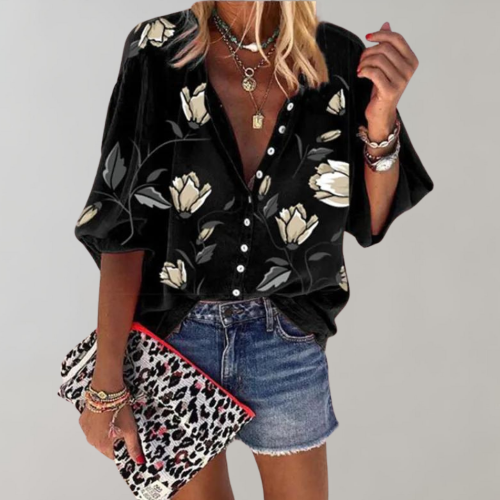 Kvinde iført sort bluse med blomsterprint, denimshorts og leopardmønstret taske. Mode, sommerstil, trendy tøj, casual look.