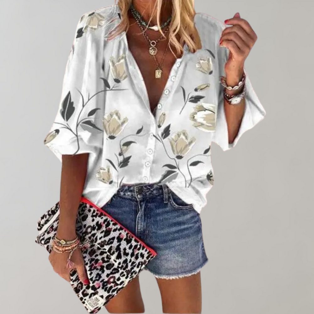 Kvinde iført hvid blomstret skjorte, denimshorts og leopardmønstret taske. Trendy sommermode, afslappet stil, smykker og tilbehør.