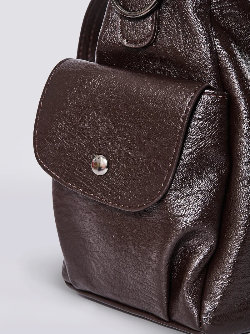 Brun læderrygsæk med lomme og sølvknap. Stilfuld og praktisk taske til hverdagsbrug. Høj kvalitet, holdbart design.