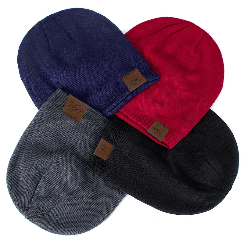 Fire farvede beanies i blå, rød, grå og sort med lædermærker. Stilfulde vinterhuer til mænd og kvinder. Perfekt til koldt vejr og mode.