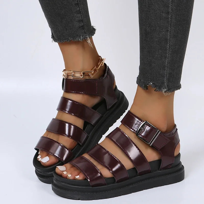 Brune lædersandaler med remme og spænder, båret af en person i sorte jeans. Moderne fodtøj til kvinder, perfekt til sommermode.