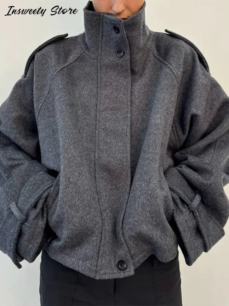 Grå uldjakke med høj krave og knaplukning, moderne design, varm og stilfuld til vintermode. Perfekt til både hverdag og festlige lejligheder.