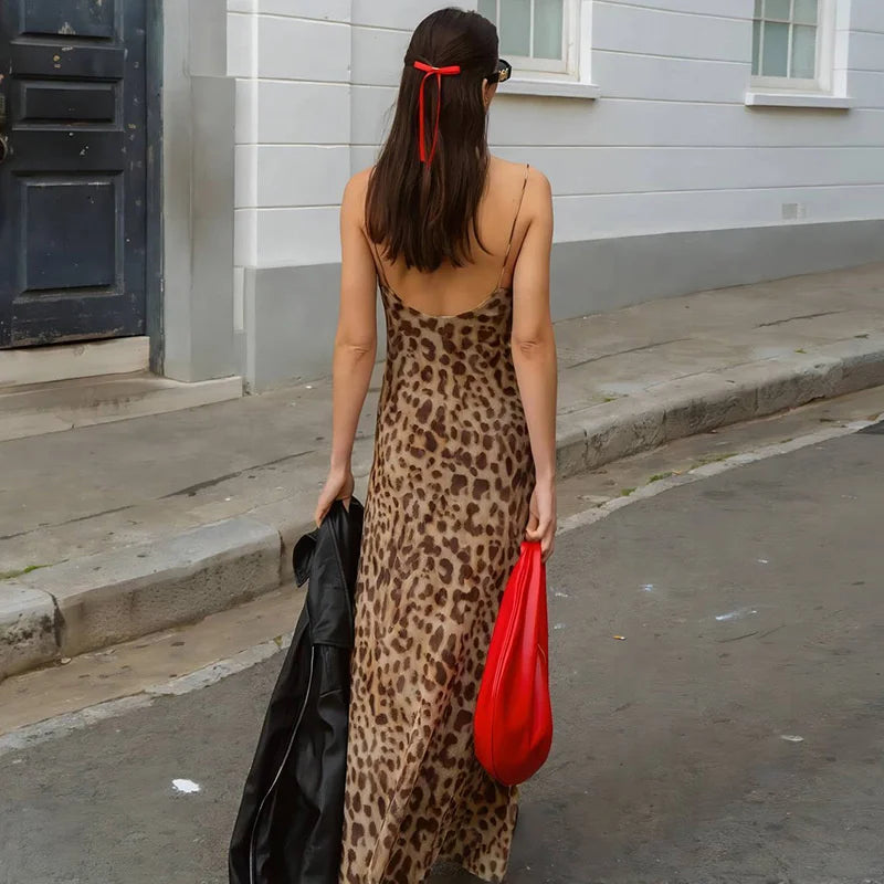 Kvinde i leopardmønstret kjole med rød taske og sort jakke på gaden. Mode, sommerkjole, trendy tilbehør, bymiljø.