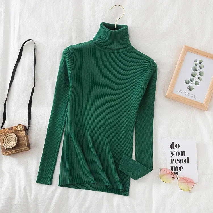 Grøn rullekrave sweater på hvid baggrund med træramme, retro kamera og solbriller. Moderne mode, vintertøj, stilfuldt design.