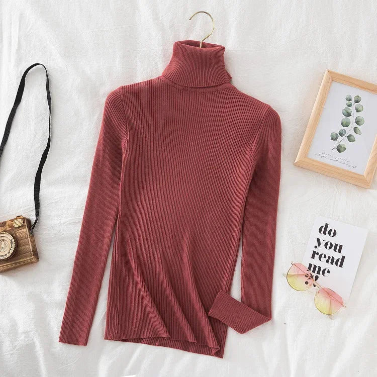 Rød rullekrave sweater på hvid baggrund, ved siden af kamera, briller og billedramme. Moderne mode, vintertøj, stilfuldt design.