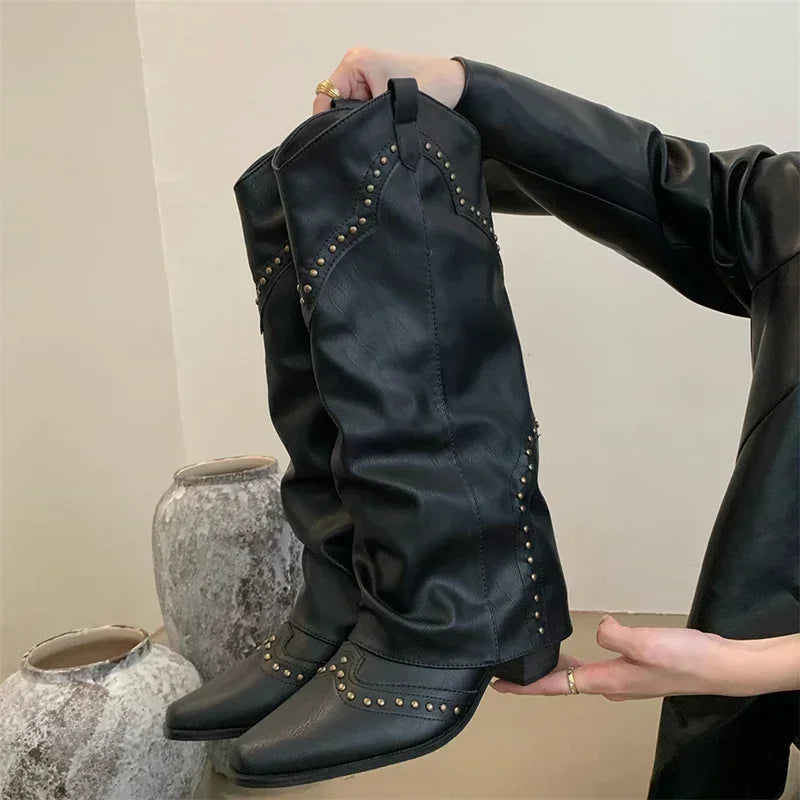 Sort læderstøvler med nitter, holdt af person i sort jakke. Moderne design, ideel til modebevidste. Perfekt til efterår og vinter.