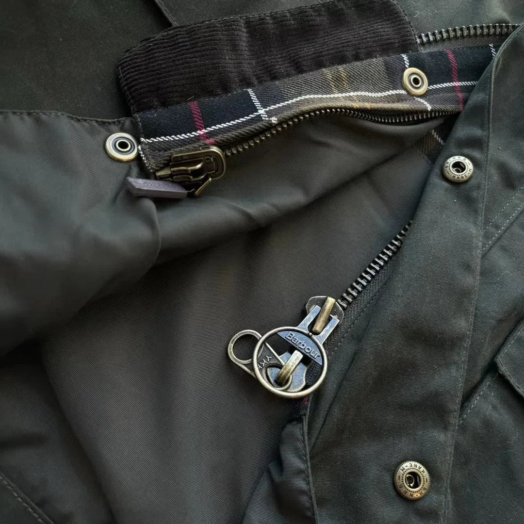 Sort jakke med lynlåsdetalje og ternet foring, Barbour logo på lynlåsen. Perfekt til efterår og vinter, stilfuld og funktionel overtøj.