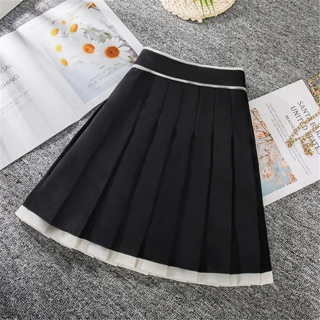Sort plisseret nederdel på grå baggrund ved siden af åbne magasiner. Elegant design, perfekt til modebevidste kvinder. Trendy og stilfuldt tøjvalg.