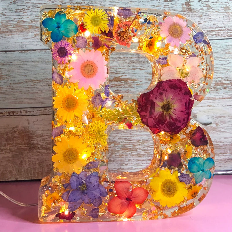 Dekorativt bogstav "B" med indlejrede tørrede blomster og LED-lys, farverig blomsterkunst, unik boligindretning, håndlavet lysende dekoration.