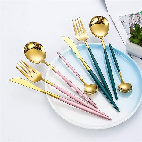 Guld- og pastelfarvet bestiksæt på hvid tallerken, moderne design, inkluderer gafler, knive og skeer, perfekt til stilfuld borddækning.