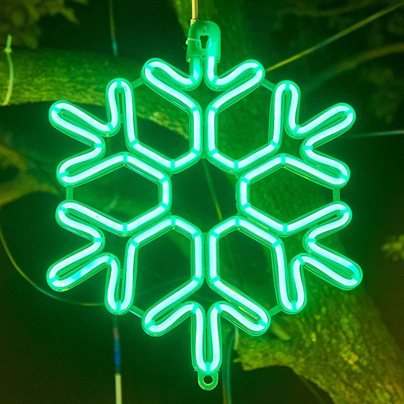 Grøn neon snefnug dekoration hængende på træ, julebelysning udendørs, vinterpynt, LED lys, energibesparende, festlig stemning.