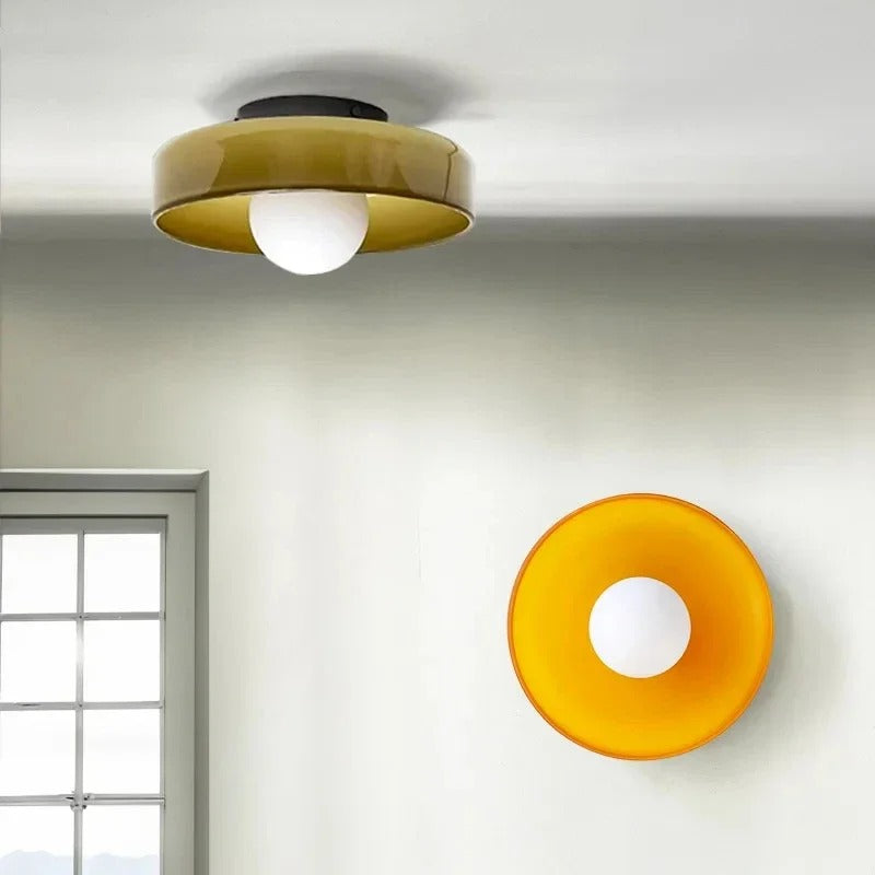 Loftlampe og væglampe i moderne design med gul skærm og hvid pære, placeret i et lyst rum med vindue. Ideel til stilfuld belysning.