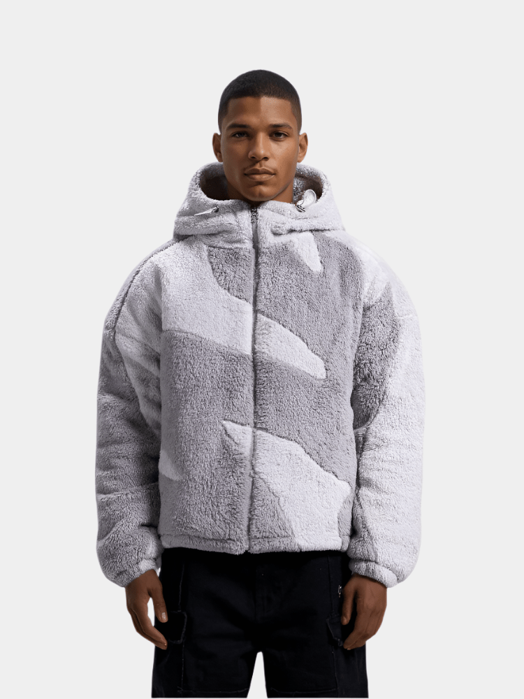 Mand iført grå og hvid camo hættetrøje i plys, stående mod hvid baggrund. Trendy vintermode, varm jakke, moderne herretøj.