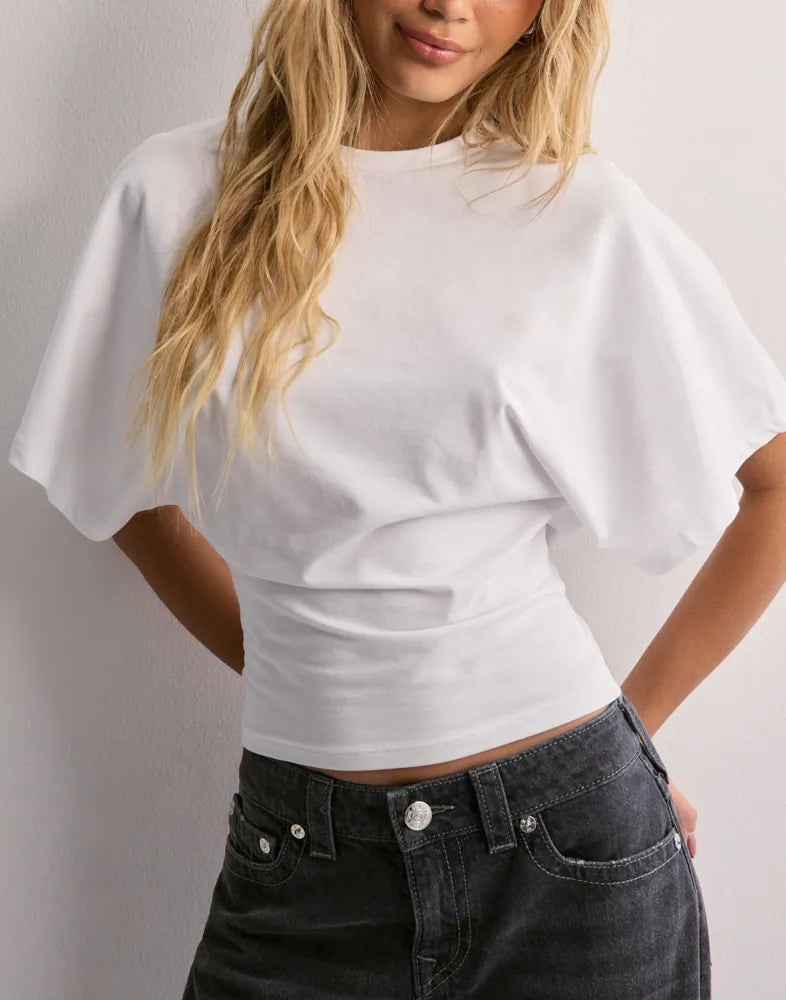 Kvinde iført hvid T-shirt med vide ærmer og sorte jeans. Moderne mode, casual stil, trendy tøj til kvinder.