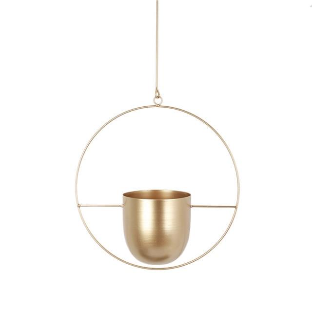 Guld hængende planteholder i moderne cirkulært design, minimalistisk indretning, stilfuld metalpotte til indendørs planter, skandinavisk boligindretning.