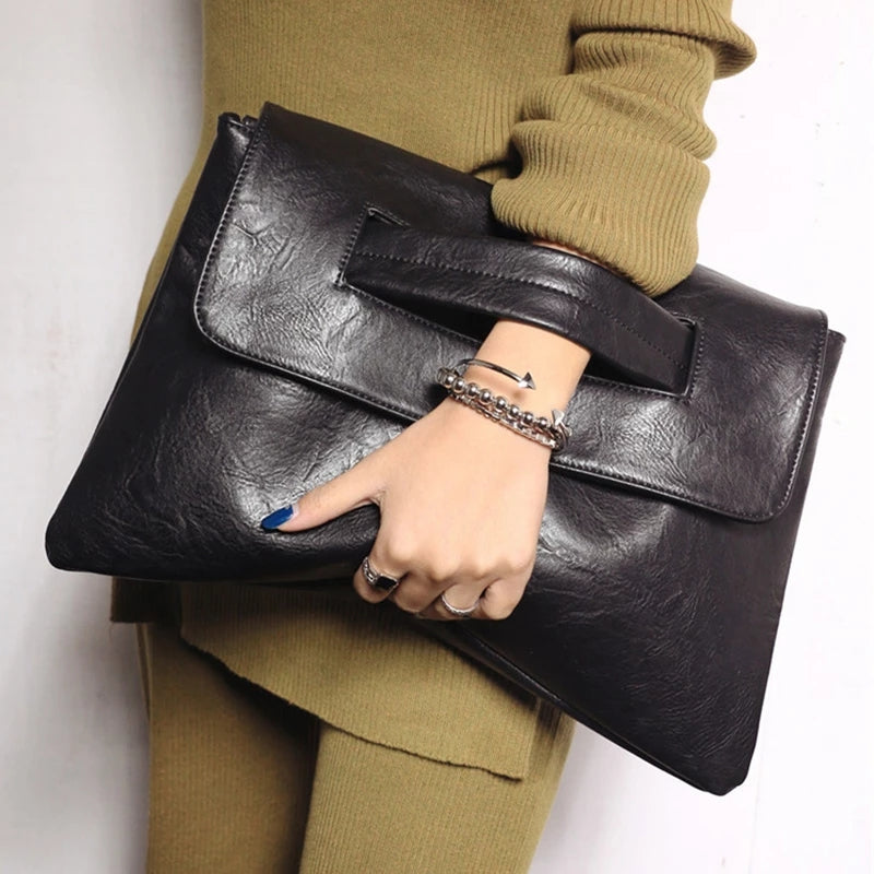 Kvinde med stor sort læder clutch taske, iført beige sweater. Elegant modeaccessory, trendy design, perfekt til stilfulde outfits.