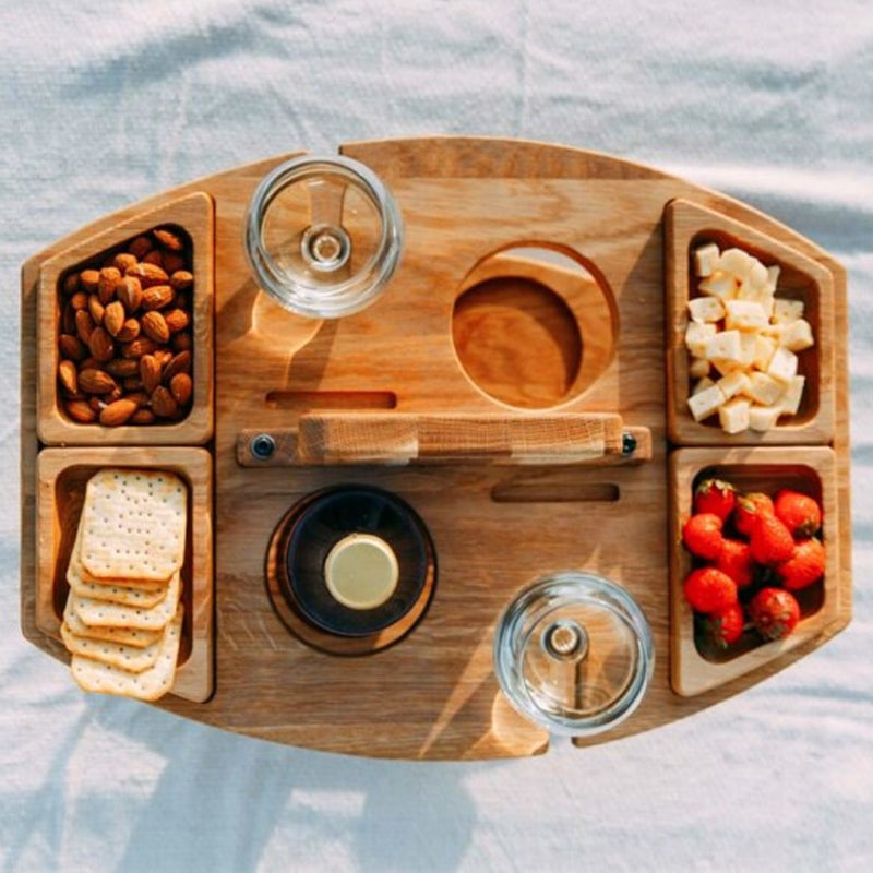Træserveringsbakke med vinholder, fyldt med mandler, ost, jordbær og kiks. Perfekt til picnic eller udendørs servering.
